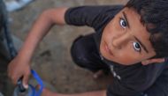 A Palestinian boy fills a canister with water from a hose in Deir el-Balah in the central gaza Strip on April 19, 2024. 