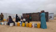 Displaced Palestinians wait by containers for water supply at their tent camp in Rafah in the southern Gaza Strip on April 26, 2024. Photo by MOHAMMED ABED / AFP