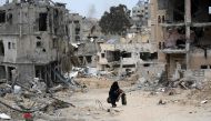 A Palestinian woman carrying some belongings walks in a neighbourhood devastated by Israeli bombing in Khan Yunis in the southern Gaza Strip on April 25, 2024. (Photo by AFP)
