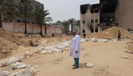 A doctor stands near bodies lined up for identification after they were unearthed from a mass grave found in the Nasser Medical Complex in the southern gaza Strip on April 25, 2024 (Photo by AFP).