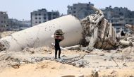 A Palestinian child transporting pieces of wood walks past a building destroyed by Israeli bombardment in Gaza City on May 3, 2024, amid the ongoing conflict between Israel and the militant group Hamas. (Photo by AFP)