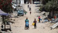 Palestinians carry recipients as they walk toward a water distribution point along a street devastated by Israeli bombardment in gaza City on May 3, 2024. (Photo by AFP)
