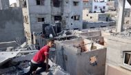 A Palestinian boy checks the destruction from the roof of a damaged house following Israeli bombardment of Rafah's Tal al-Sultan district in the southern Gaza Strip on May 7, 2024. (Photo by AFP)