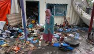 A Palestinian woman inspects the debris of a container at an UNRWA school used to shelter displaced people, after it was hit in Israeli bombardment on Nusseirat in the central Gaza Strip on May 6, 2024. (Photo by AFP)
