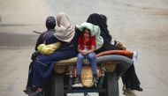 Palestinians sit on an animal pulled cart as they move to safer areas in rafah, in the southern Gaza Strip. (Photo by AFP)
