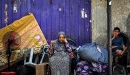 An elderly woman and child wait with belongings before evacuating from Rafah in the southern Gaza Strip on May 11, 2024. (Photo by AFP)