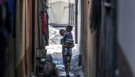 A Palestinian boy carries a toddler in an alley in Deir el-Balah in the central gaza Strip on May 15, 2024 . (Photo by AFP)