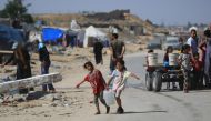 Displaced Palestinian children carry water in a makeshift camp in Khan Yunis in the southern Gaza Strip on May 24, 2024. Photo by Eyad BABA / AFP.