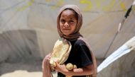 A Palestinian girl carries bread and potatoes at a camp for displaced people in Deir al-Balah in the central Gaza Strip on May 30, 2024. (Photo by Bashar Taleb / AFP)

