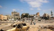 Palestinian men walk past damaged buildings after an overnight Israeli strike in al-Bureij camp in the central Gaza Strip on June 3, 2024. (Photo by Eyad Baba / AFP)