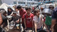 Palestinians queue for meal rations at a communal food distribution point in al-Bureij refugee camp in the besieged Gaza Strip on June 3, 2024. Photo by Eyad BABA / AFP