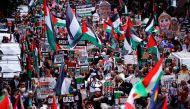 Protesters hold placards and wave Palestinian flags as they take part in a 