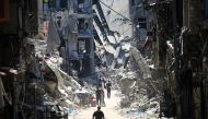 Palestinian men walk along a narrow street past destroyed buildings in Khan Yunis, in the southern Gaza Strip on June 11, 2024. Photo by Eyad BABA / AFP