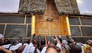 Worshippers pray before and touch the doors of the Kaaba, Islam's holiest shrine, at the Grand Mosque in Saudi Arabia's holy city of Mecca on June 13, 2024. (Photo by Fadel Senna / AFP)