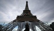 A person walk past the Eiffel Tower, decorated with the Olympic rings for the upcoming Paris 2024 Olympic Games, on June 14, 2024 in Paris. (Photo by Valentine Chapuis / AFP)