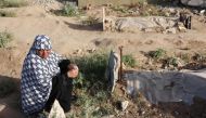 A Palestinian woman reacts near the shallow grave of a relative in the eastern al-Tuffah neighbourhood of Gaza City on June 16, 2024. (Photo by Omar Al Qattaa / AFP)