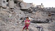 A Palestinian girl, dressed in new clothes, sits amid the rubble of a destroyed building as she celebrate the Eid al-Adha in Khan Yunis in the southern Gaza Strip, on the first day of the Muslim holiday marking the end of the hajj pilgrimage to Makkah, on June 16, 2024. (Photo by Bashar TALEB / AFP)
