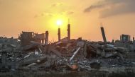 The sun rises over destroyed buildings in Khan Yunis, in the southern Gaza Strip on June 22, 2024. (Photo by Bashar Taleb / AFP)