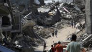 People walk along a road between the rubble of buildings destroyed during Israeli bombardment in Khan Yunis on the southern Gaza Strip on June 23, 2024. (Photo by Eyad BABA / AFP)