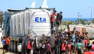 People gather to fill up their water containers from a truck loaded with water cisterns in Rafah in the southern Gaza Strip on June 25, 2024. Photo by Eyad BABA / AFP.