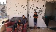 A Palestinian boy hugs a woman a she speaks to a girl while sitting on the balcony of a home damaged in previous Israeli bombardment, as some residents return to the city of Khan Yunis, in the southern Gaza Strip on June 30, 2024. (Photo by Eyad Baba / AFP)
