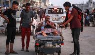 A man is transported on a hospital bed as displaced Palestinians leave an area in east Khan Yunis. (Photo by Bashar Taleb / AFP)