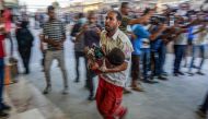 A paramedic carries a wounded child by Israeli bombardment to the emergency ward at Nassr hospital in Khan Yunis, on the southern Gaza Strip on July 9, 2024. (Photo by Bashar Taleb / AFP)