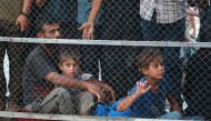 People sit behind a fence as they watch the arrival of victims wounded or killed in Israeli bombardment near Khan Yunis into Nasser hospital on July 9, 2024. (Photo by Bashar Taleb / AFP)