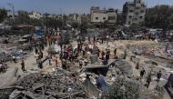 Palestinians look at the debris of destroyed tents and make shift housing structures following an Israeli military strike on the al-Mawasi camp for internally displaced people (IDP), near the city of Khan Yunis, southern Gaza Strip on July 13, 2024.(Photo by Bashar TALEB / AFP)
