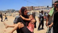 A Palestinian woman carries an injured child to the Nasser hospital in Khan Yunis on July 13, 2024, one of the health establishments to which casualties were rushed after an Israeli strike killed at least 71 people and injured many others at the Al-Mawasi camp for the war displaced in the south of the Palestinian territory, according to the health ministry. (Photo by Eyad BABA / AFP)
