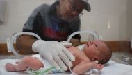 The newborn being caressed by his grandfather as he lies in an incubator at the al-Awda hospital in Deir el-Balah on July 20, 2024. (Photo by Eyad Baba / AFP)