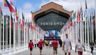 Participants of the Paris 2024 Olympics and Paralympics game walk in front of the cafeteria of the Olympic Village, in Saint-Denis, northern Paris, on July 22, 2024. (Photo by Michel Euler / Pool / AFP)