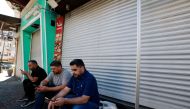 Palestinian men follow the news of the assassination of Hamas chief, Ismail Haniyeh in Iran, outside closed shops in central Ramallah in West Bank during a general strike on July 31, 2024. Photo by Jaafar ASHTIYEH / AFP