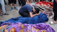 A young man mourns over the corpse of a person killed in an Israeli strike on a school used by displaced Palestinians as a temporary shelter in Gaza City on August 10, 2024, that killed more than 90 people. (Photo by Omar AL-QATTAA / AFP)