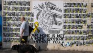 People walk past posters of Israelis held hostage by Palestinian militants in Gaza since October 7, on a street in Tel Aviv on August 13, 2024. (Photo by Oren Ziv / AFP)