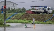 A worker walks in a flooded road in the wake of 