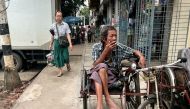 A trishaw driver smokes as he waits for passengers in Yangon on August 13, 2024. (Photo by Saiaung Main / AFP)
