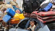 A child peeks out from the window of a car as Palestinians flee with their belongings Deir el-Balah in the central Gaza Strip on August 16, 2024. (Photo by Eyad Baba / AFP)