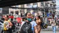 A woman wearing a face mask crosses a street with other people in Manila on August 21, 2024. (Photo by Jam Sta Rosa / AFP)