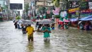 People carrying umbrellas, wade through a flooded street amid rainfall in Feni on August 22, 2024. (Photo by AFP)
