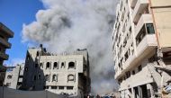 Palestinians watch as smoke rises from a building hit by an Israeli strike after a warning from the army to its occupants to evacuate the premises, in the Rimal neighbourhood of central Gaza City on August 21, 2024. (Photo by Omar Al-Qattaa / AFP)
 