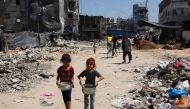 Palestinian children carry pots of soup near a food distribution point in the Jabalia refugee camp in northern Gaza Strip on August 21, 2024. (Photo by Omar Al-Qattaa / AFP)