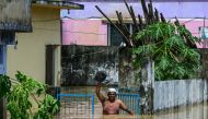 A man carrying his belongings wades through flood waters in Feni, in south-eastern Bangladesh, on August 23, 2024. Photo by MUNIR UZ ZAMAN / AFP.