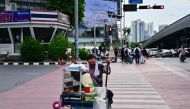 A vendor pushes his cart as he crosses a street in Bangkok on August 23, 2024. (Photo by MANAN VATSYAYANA / AFP)