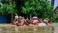 People carrying relief materials wade through flood waters in Feni, in south-eastern Bangladesh, on August 24, 2024. Photo by Munir Uz Zaman / AFP.