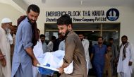 People move the body of a bus accident victim from a hospial in Kahuta, Punjab province on August 25, 2024. (Photo by Aamir QURESHI / AFP)