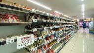 Empty shelves of rice are pictured in a supermarket with a notice written: 