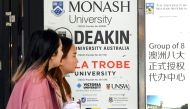 Women walk past signage advertising Australian universities in Melbourne's central business district on June 10, 2020. Photo by William WEST / AFP