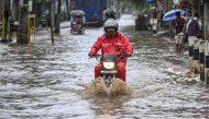 A man riding a motorbike moves through a flooded street after heavy rainfall during monsoon in Guwahati on August 20, 2024. Photo by Biju BORO / AFP.
