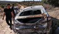 People inspect a destroyed vehicle after an Israeli army raid along a road between Jenin and Tubas in the north of the occupied West Bank on August 28, 2024. (Photo by Zain JAAFAR / AFP)
